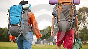 Rear View Of Young Couple Meeting At Summer Music Festival With Camping Equipment