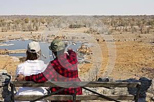 Rear view of young couple observing animals in African savannah, Etosha National Park, Namibia