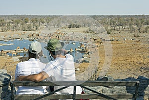 Rear view of young couple observing animals in African savannah - travel concept