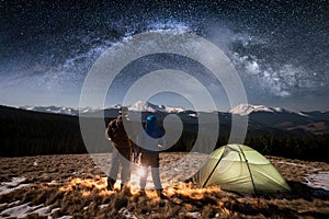 Rear view young couple tourists having a rest in the camping at nigh under night sky full of stars and milky way