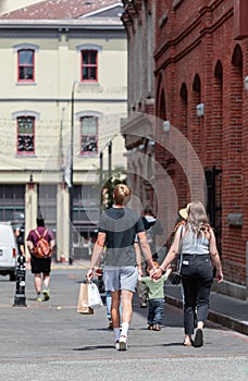Rear view of a young couple walking down the street holding hands and shopping bags