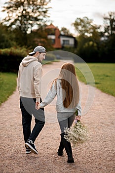 rear view of young couple of woman and man walks at street and looking at each other. Love story