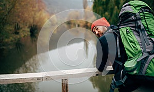 Rear view of young handsome hiker man in red hat and travel equipment enjoy the beautiful nature view.