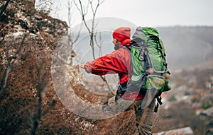 Rear view of young hiker man hiking in mountains dressed in red clothes exploring new places.