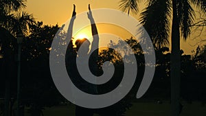 Rear view of a young male doing Surya Namaskar in a silhouette background