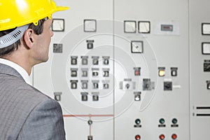 Rear view of young male supervisor examining control room in industry