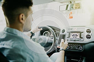 Rear view of young man in formalwear using his smart phone while sitting in the car