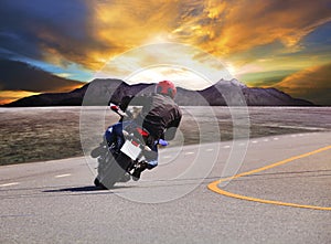 Rear view of young man riding motorcycle in asphalt road curve w