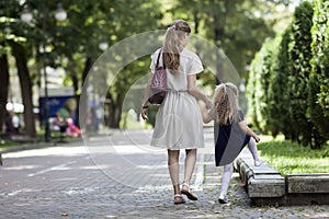 Rear view of young mother walking with little girl daughter in