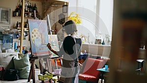 Rear view of Young painter girl in apron painting still life picture on canvas in art-class