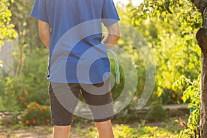 rear view of young person standing outdoor and piss under the trees photo