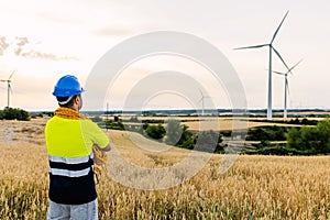 Rear view of young professional worker looking away at wind turbine farm