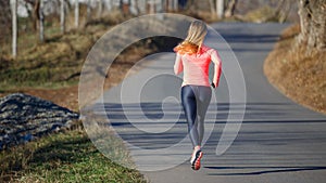 Rear view of young running woman on the road in cold winter morning
