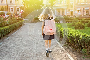 Rear view of young schoolgirl in uniform with backpack going to