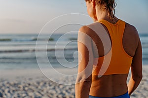 Rear view of young sportive woman at beach.