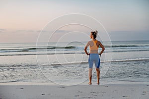 Rear view of young sportive woman at beach.