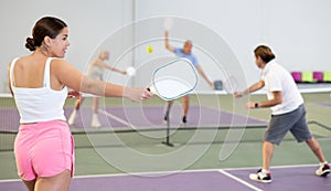 Rear view of young woman playing pickleball on indoor court