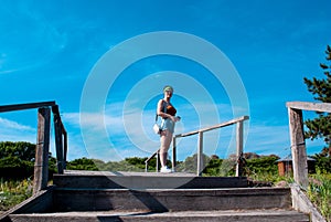 Rear view of a young woman in short shorts climbing stairs in a summer park on a sunny day