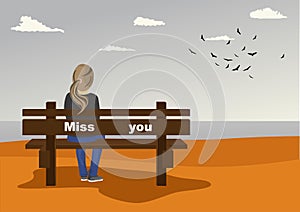 Rear view of young woman sitting on bench on seashore with miss you text on it in autumn