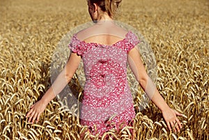 Rear view of young woman standing in wheatfield