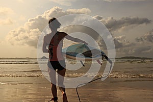 Woman surfer with white surfboard walking to the sea