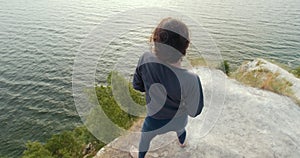 Rear view of young woman warming-up on the edge of a cliff at sunrise