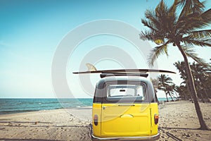 Rear of vintage car parked on the tropical beach seaside with a surfboard on the roof