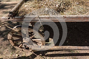 Rear wheel of an old cart with hay close-up. Rustic background