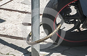 Rear wheel of powerful motorcycle locked to sign pole