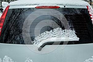 rear window of car with windshield wiper covered with snow.
