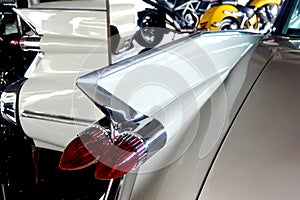 The rear wing of a white 1959 retro car, reflected in the mirrors, close-up