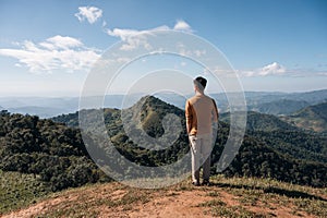 Young asian man standing with looking at mountain view on top of hill at national park