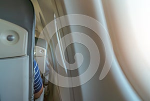 Rearview of airplane seat near plane window. Economy class airplane. Inside of commercial airline. Small space between passenger