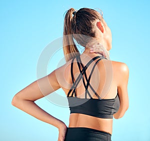 Rearview beautiful woman practising yoga exercise on the beach. Young female athlete suffering with neck pain while