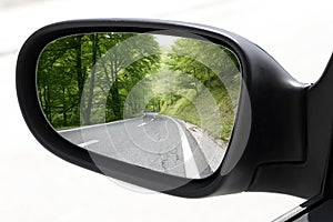 Rearview car driving mirror view forest road