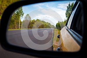 Rearview car driving mirror view forest road