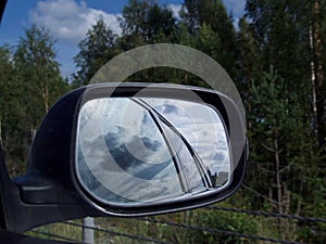 Rearview car driving mirror view green forest road