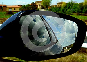The rearview of a car with reflections of the clouds