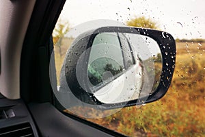 Rearview mirror against the background of an autumn landscape. Traveling by car off-road. View from salon