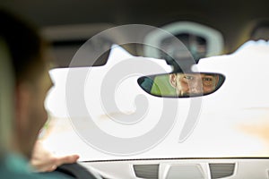 Rearview mirror reflection of man driving car