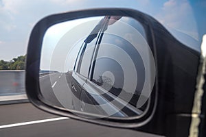 rearview mirror view of a car traveling at high speed on a toll road