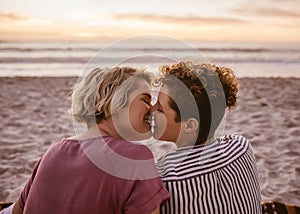 Romantic young lesbian couple kissing during a beach sunset