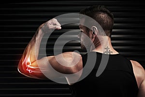 Pain is just a part of the package. Rearview shot of an athletic young man flexing with an elbow injury in the studio.
