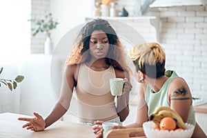 Reasoning african american woman with coffee and listening girlfriend