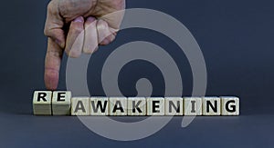 Businessman turns cubes and changes the word 'awakening' to 'reawakening'. Beautiful grey background  copy