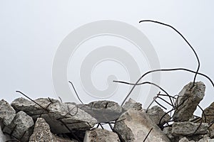 The rebar sticking up from piles of brick rubble, stone and concrete rubble against the sky in a haze