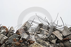 The rebar sticking up from piles of brick rubble, stone and concrete rubble against the sky in a haze