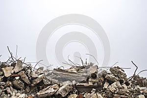 The rebar sticking up from piles of brick rubble, stone and concrete rubble against the sky in a haze