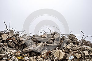 The rebar sticking up from piles of brick rubble, stone and concrete rubble against the sky in a haze