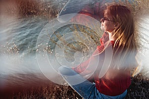 Rebel careless ginger girl in red sweater smoking near sea in sunrise